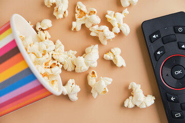 bucket of popcorn, tv remote on beige background
