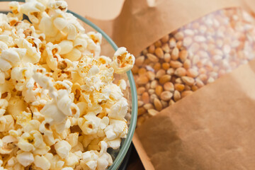 Cooked Popcorn in glass bowl and corn grains in a paper box