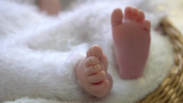Slow Motion Small feet of a newborn baby on the bed. The concept of motherhood