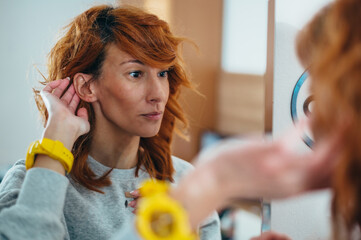 Woman putting a hearing aid in her ear
