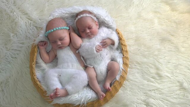 Two adorable newborn twin babies asleep on a soft blanket