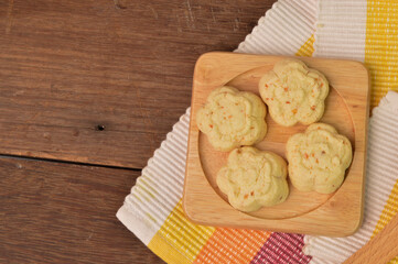 Malaysian traditional cookies called as KUIH BANGKIT CHEESE on wooden plate served during eid Mubarak