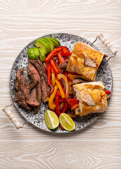 Fajitas sandwiches made from traditional Mexican dish Beef fajita and white bread served with ripe avocado on white wooden rustic background from above, American Mexican food healthy snack