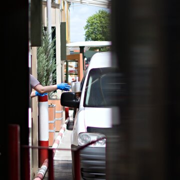 Seller hand giving package of fast food in driver service restaurant. Blurred foreground