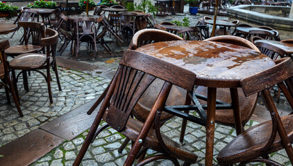 Empty street cafe with small round tables and wooden chairs after rain at the cloudy day