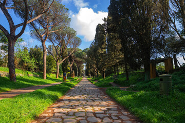 Walking along the ancient appia, the road to Rome and the Roman Empire on a spring day. Beautiful detail of the paving of the maritime pines and cypresses that stand out in the blue sky.