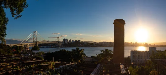 Fotobehang Pôr do sol e torre de indústria desativada   e a panorâmica da Ponte Hercílio Luz , Santa Catarina, Brasil, florianopolis © Fotos GE