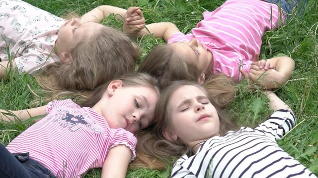 Slow Motion Happy children lying on grass. Funny kids playing in park. Top view