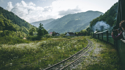 Fototapeta na wymiar The romanian mocanita steem train going through the green mountains