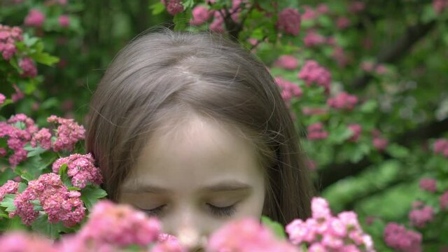 Slow Motion Pretty little girl with flowers over blooming nature background