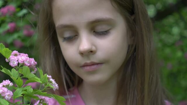 Pretty little child girl with flowers over blooming nature background close up. 