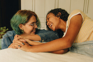 Pareja de novias lesbianas se toman de la mano mientras se ríen en un momento de diversión en su habitación 