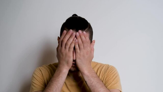 Young handsome European Caucasian man with beard shouts no and grabs his head with both hands. Person depicts the emotions of anger on white background.