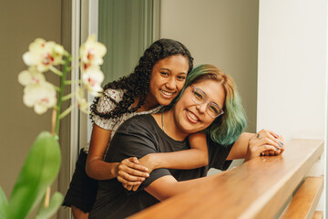  Retrato frontal de pareja de jóvenes lesbianas expresan su cariño mediante un abrazo en su casa