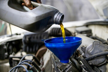 technician worker pouring engine oil. car maintenance at service station or workshop. selective...