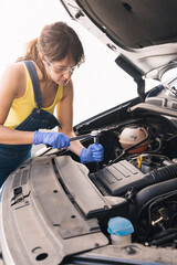 young brunette girl mechanic fixing a car
