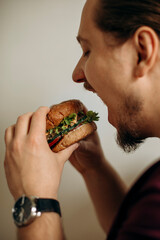 juicy fresh burger in the hands of the hungry guy. man bites a fresh hamburger. juicy fresh burger with multigrain bun.