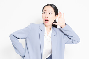白バックの前に立って、聞き耳を立てる女性