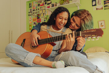 Pareja de jóvenes lesbianas se divierte tocando la guitarra juntas en su habitación