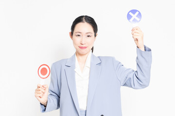 白バックの前に立って、OKとNGのプラカードを持っている女性