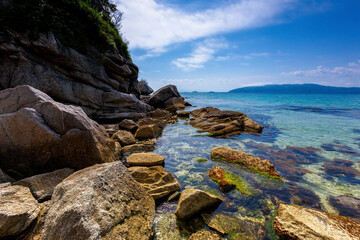 Fototapeta na wymiar Beautiful summer landscape with Furugelm island. Rocky coast of a protected island in the Primorsky region. The stone slabs, of natural origin, flow smoothly into the blue sea.