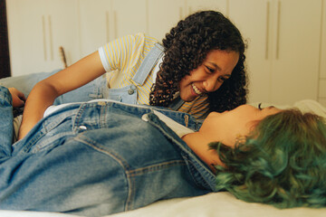 Joven afro peruana lesbiana observa a su novia recostada en su cama con una sonrisa
