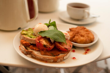 English breakfast, toast with bacon, avocado and egg on white plate.