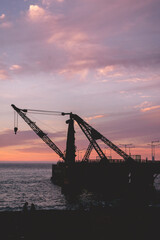 Fototapeta na wymiar Silhouette of crane at harbor in the sunset with beautiful purple and orange sky