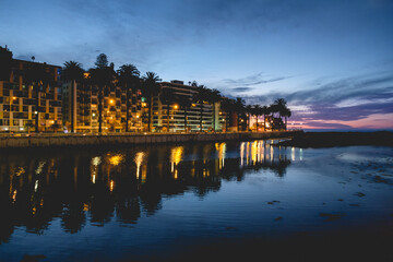 Beautiful panoramic view of the Marga Marga river, the ocean, palms, buildings with lights and reflections at the sunset, Viña del Mar, Chile