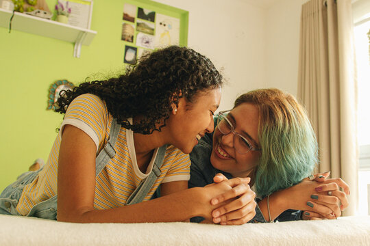 Jóvenes lesbianas sonriendo mientras se observan una a la otra sobre la cama 