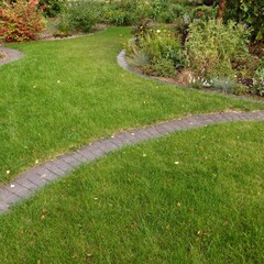 Backyard Garden Modern Design Landscaping. Landscaped Decorative Garden Winding Pathway Or Walkway From Black Bricks. Back Yard Lawn With Curved Brick Paving Path To Country House.