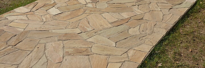 Garden landscaping with Pavement from Tiled Limestone. Backyard Garden Shaded Footpath from Tiled Stone Slabs. Flagstone Walkway in The Garden. Shady Pathway From Stone Tiles In The Park.