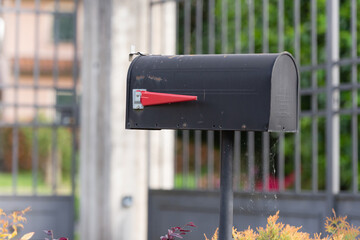 Street mailbox in Barga. A mailbox in front of a house in the Italian Mountains. Stylish black mailbox with red Flag.