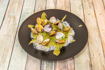 Food fusion of clams in green sauce on a bed of Asian noodles