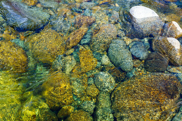 Multicolored stones at the bottom of the crystal clear Pemigewasset River in spring. Flowing water of the Franconia waterfall by the lincoln woods trail on the White Mountains National Forest, NH