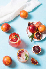 Blood orange cocktails with fresh fruits on blue table background. Summer cocktails, lemonade, refreshing drinks, low alcohol mocktail, party concept. Flat lay, top view