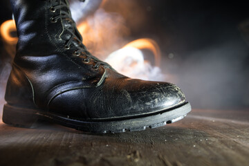 War concept. Old military shoe in a dark toned foggy background. Creative concept of conflict...