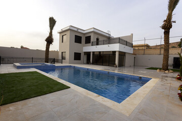Exterior modern white villa with pool and garden, nobody inside
