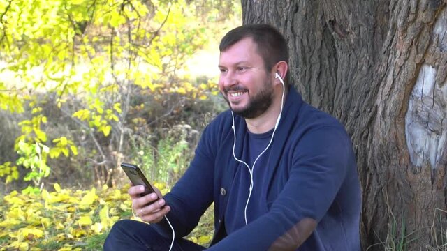 Slow Motion Happy caucasian man listening to music in autumn park