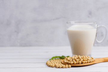Soy and soy milk in a glass with soybeans in wooden bowl background