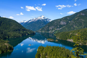 Diablo Lake in the North Cascades of Washington State under a blue sky with a beautiful reflection of Davis Peak mountain in the fresh water