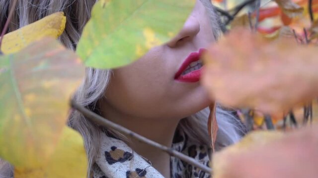 Slow Motion Young pretty girl portrait with yellow mapple leaf closed face 