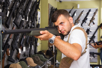 Fototapeta na wymiar Two young men selecting pneumatic gun in military shop