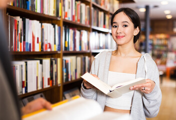 Young girl student looking for information in books at bookstore