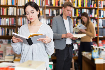 Young female student looking for information in books at bookstore