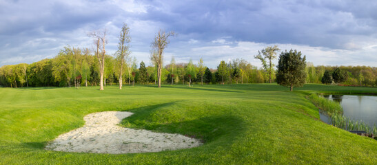 golf course in the park, sand trap and lake. Sports ground for recreation.