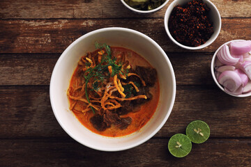Local northern Thai food Egg noodle curry with beef on wood background
