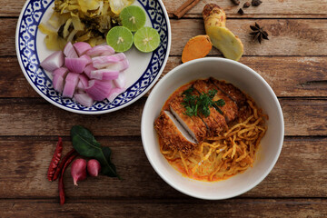 Local northern Thai food Egg noodle curry with fried pork on wood background