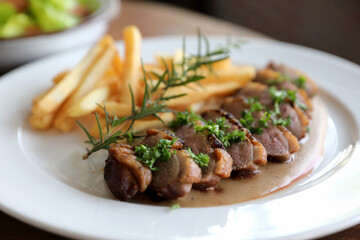 Duck magret confit with chips on wood table