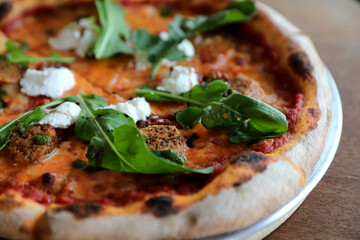 Italian Sausage and rocket salad pizza on wood background